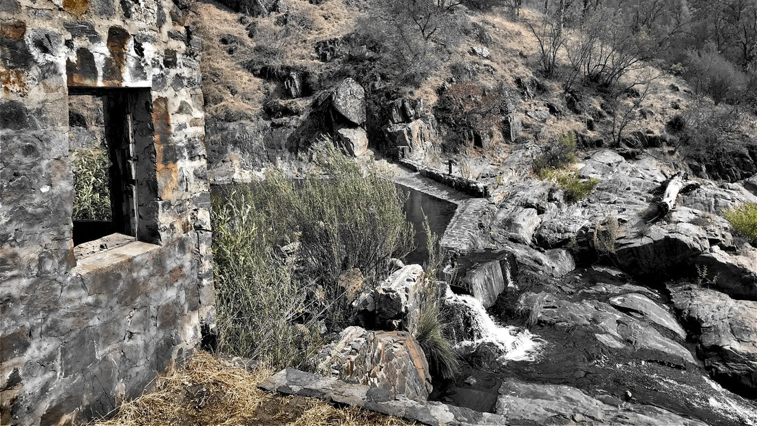 Old stone ruin beside a small waterfall on a creek