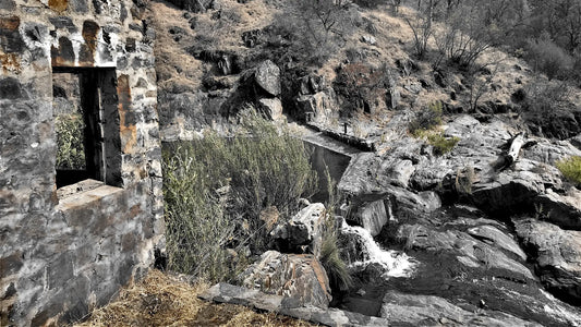 Old stone ruin beside a small waterfall on a creek